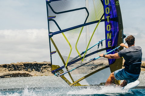 Voile de windsurf de course Duotone Warp_Fin lors d'une session de windsurf sur une côte rocheuse en pleine mer
