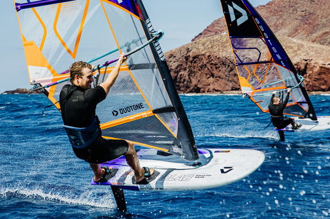 Duotone Falcon Foil D/LAB windsurf board while foiling at the ocean coast with rocky cliffs