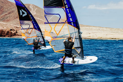 Duotone Falcon Foil D/LAB windsurf board during wing foiling at a rocky coastal landscape