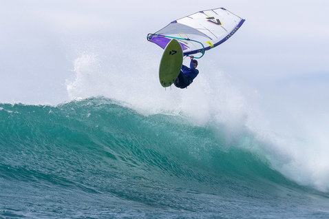 Duotone Windsurfing Ultra Grip [Quad] D/LAB windsurf board during wave riding at ocean beach in teal green, olive green and white