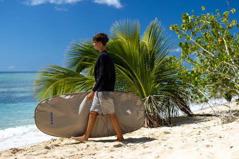 Duotone Sky Style Wing Boardbag Single beim Tragen am Strand in sandbeige