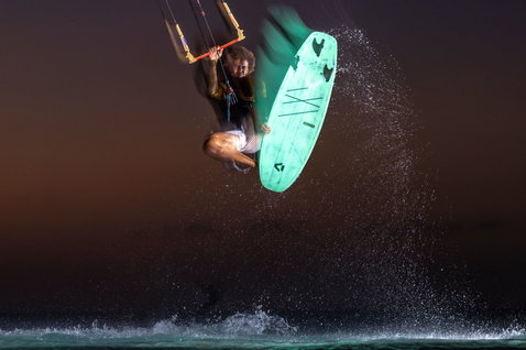 Duotone Whip SLS kiteboard kitesurfing on the ocean at dusk