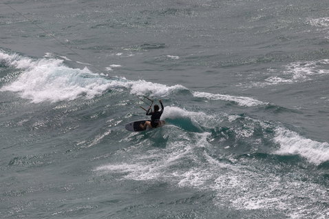 Tabla de kitesurf Duotone Whip D/LAB durante kitesurf en océano abierto con olas rompientes
