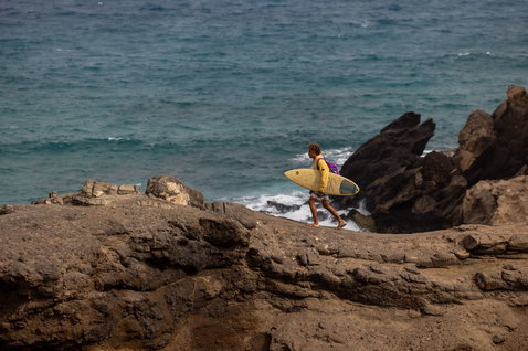 Duotone Blur SLS surfboard durante il surf sulle onde su una costa oceanica rocciosa