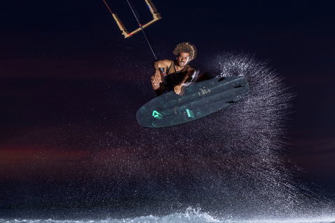 Duotone Provoke kiteboard freestyle strapless 5'1" durante il kitesurf sull'oceano di notte