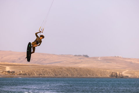 Duotone Provoke kite surfboard 5'1" durante il kitesurf su oceano costiero con colline aride sullo sfondo