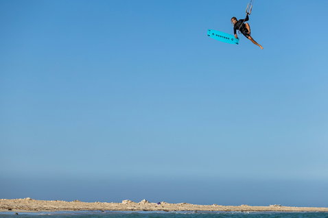 Duotone TS Big Air SLS kiteboard twin-tip lors d'une session de kitesurf sur une plage océanique