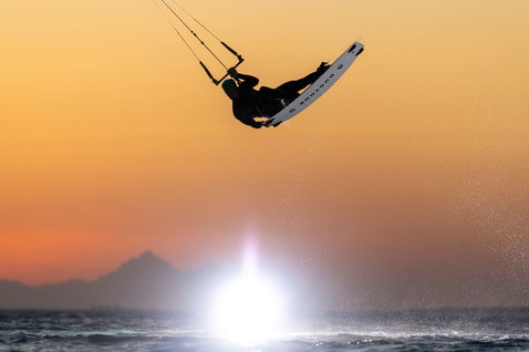 Duotone TS Park twin-tip kiteboard en kitesurf dans l'océan avec côte et silhouette de montagne