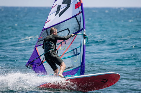Duotone Blitz D/LAB windsurf board during windsurfing on open ocean in crimson red and purple