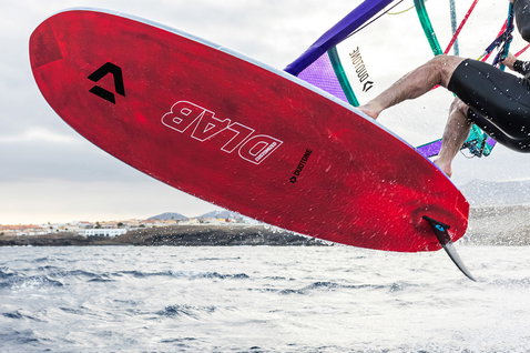 Duotone Blitz D/LAB Customized windsurf board during windsurfing on coastal ocean with village in background