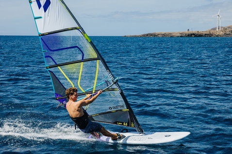Duotone Blitz D/LAB windsurf board during windsurfing on the ocean with rocky coastline
