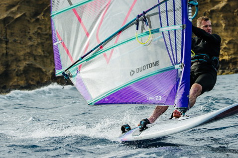 Duotone Blitz D/LAB windsurf board during freeride on the ocean with rocky cliffs