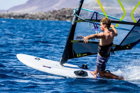 Duotone Blitz D/LAB windsurf board during windsurfing on the open ocean with rocky coastline
