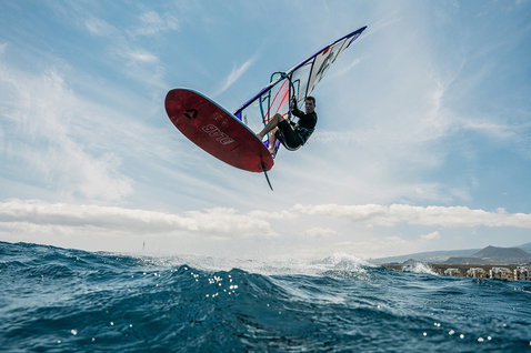 Duotone Blitz D/LAB windsurf board during windsurfing on the ocean with coastal town in background