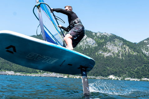 Planche de foil windsurf Duotone Stingray D/LAB en train de faire du foiling sur un lac alpin