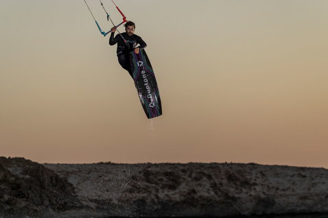 Planche de kitesurf twin-tip Duotone Jaime Concept Blue en kitesurf sur une plage rocheuse