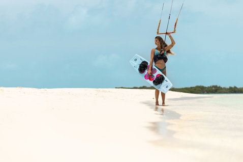 Duotone Soleil SLS Twin-Tip-Kiteboard beim Kitesurfen an einem tropischen Strand mit weißem Sand