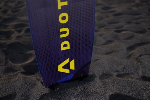 Kiteboard twin-tip Duotone Shred lors d'une session de kitesurf sur une plage de sable volcanique sombre