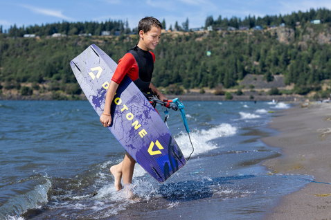 Duotone Shred twin-tip kiteboard en kitesurf sur un lac avec des collines boisées en arrière-plan