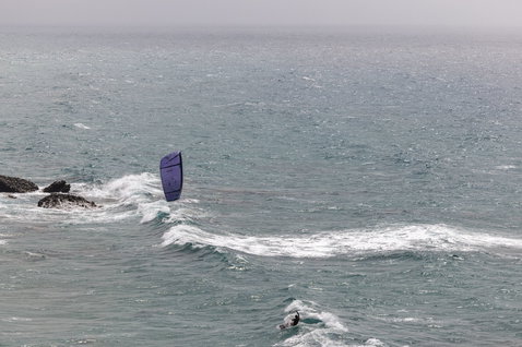 Duotone Neo LEI Kite beim Wellenreiten an einer Ozeanküste mit Felsvorsprung