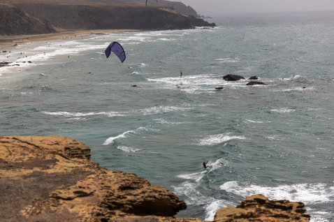 Duotone Neo LEI Kite beim Wellenreiten an einem Felsstrand mit Klippen