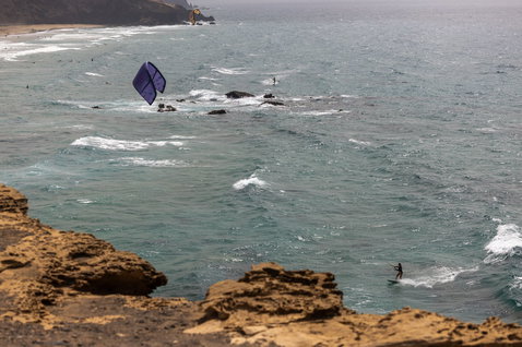 Duotone Neo Concept Blue LEI Kite beim Wellenreiten an der Ozeanküste mit Felsen