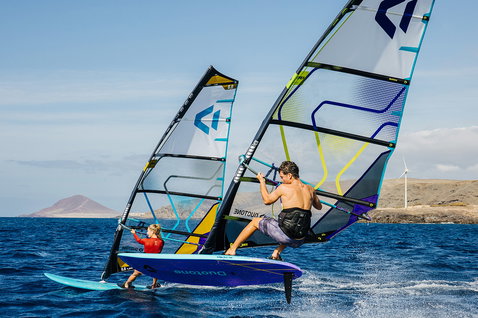 Duotone E_Pace voile freeride pendant le windsurf sur l'océan avec île rocheuse et éoliennes