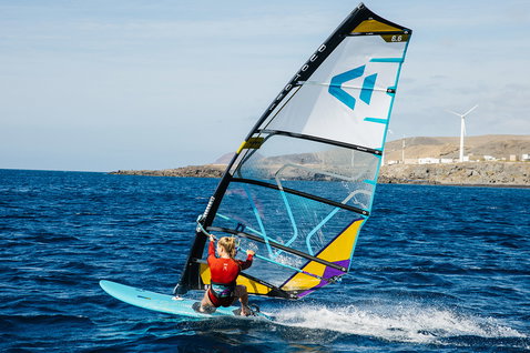 Duotone E_Pace voile freeride 6,6 m² lors de la planche à voile sur océan ouvert avec côte rocheuse et éoliennes en bleu marine foncé