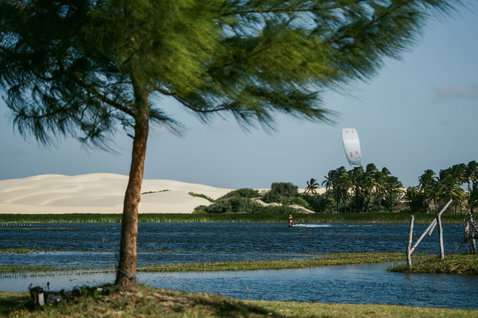 Duotone Evo SLS LEI kite during kitesurfing in a tropical lagoon with sand dunes and palm trees