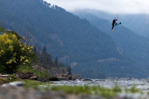 Duotone Rebel D/LAB LEI kite durante il kitesurf in una valle fluviale di montagna