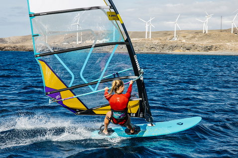 Duotone Eagle planche de windsurf lors d'une session de windsurf sur l'océan près d'une côte rocheuse avec éoliennes
