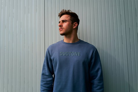 Sweat unisexe Duotone Signature Originals en bleu ardoise porté par un homme devant un mur gris