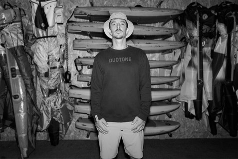 Icon bucket hat in dark charcoal in an indoor gear storage room with surfboards and kite equipment
