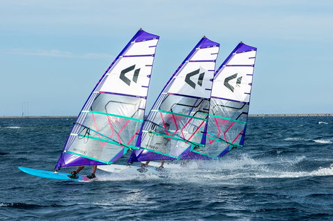 Freeride sail during windsurfing on the ocean near a harbour breakwater
