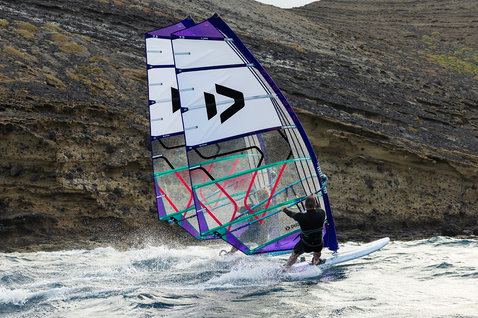 Freeride sail during windsurfing along rocky coastal cliffs and open ocean