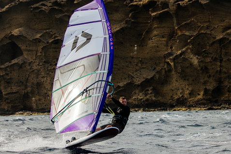 Duotone X Pace freeride sail during windsurfing on a coastal ocean with rocky cliffs