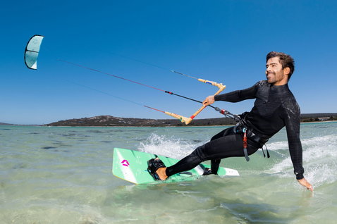 Duotone Spike planche de kitesurf twin-tip lors du kitesurf dans un lagon turquoise peu profond avec plage de sable