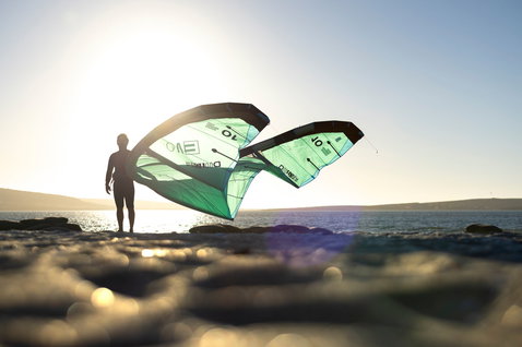 LEI kite durante il kitesurf su una spiaggia oceanica con riva rocciosa