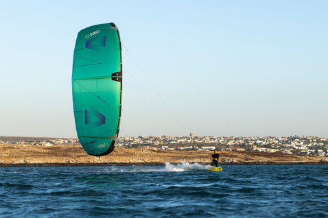 Duotone Evo LEI kite durante il kitesurf in una baia costiera con paese sullo sfondo