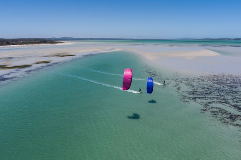 Duotone Juice SLS twin-tip kiteboard lors du kitesurf dans un lagon côtier peu profond avec des bancs de sable blanc