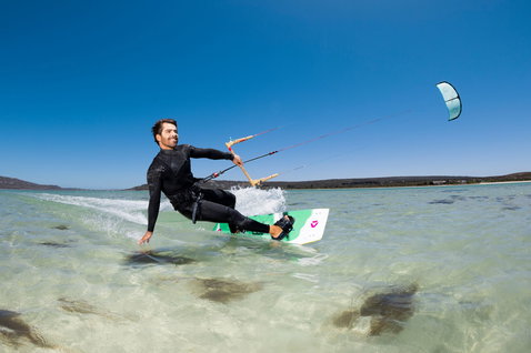 LEI kite during kitesurfing in a shallow coastal lagoon with sandy beach and hills