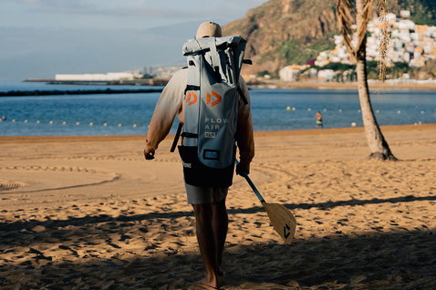 Duotone Flow Air SLS planche SUP gonflable en sac à dos lors du stand-up paddle sur la plage au coucher du soleil