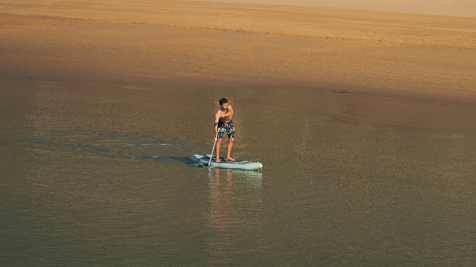Duotone Blitz Air SLS inflatable SUP board during paddling on shallow golden-hour waters