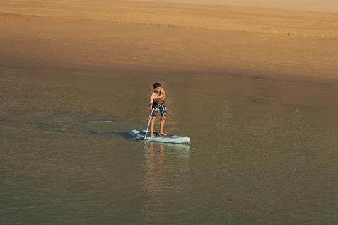 Duotone Blitz Air SLS inflatable SUP board during paddling on shallow golden-hour waters