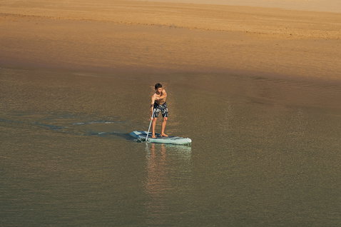 Planche SUP gonflable Duotone Blitz Air SLS lors d'une session de paddle en eaux peu profondes à la lumière dorée