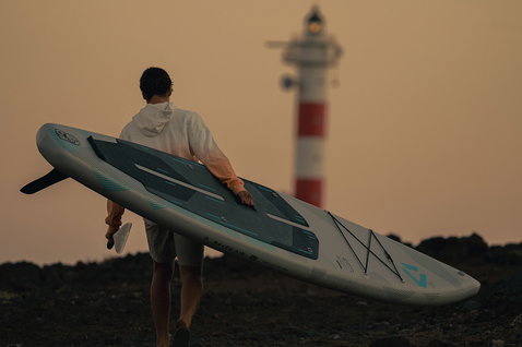 Planche de SUP gonflable Duotone Raven Air SLS lors d'une randonnée côtière rocheuse au coucher du soleil
