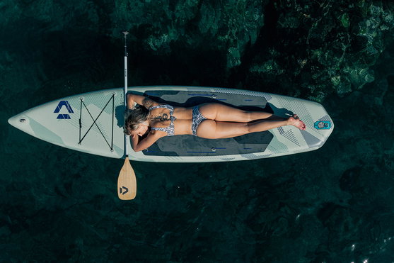 Duotone Blitz Air SLS inflatable SUP touring board viewed from above with person relaxing on clear tropical water