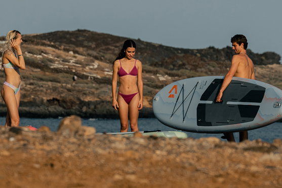 Duotone Flow Air SLS inflatable SUP board during paddleboarding at a rocky coastline at golden hour