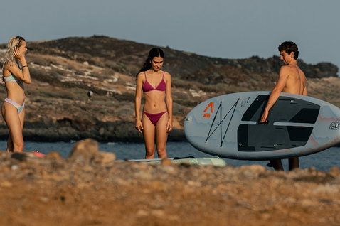 Duotone Flow Air SLS iSUP during stand-up paddleboarding at a rocky coastal beach in golden-hour light