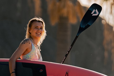 Pagaie SUP Duotone Carbon 100 Slim Adj. lors d'une session de stand-up paddle sur fond de falaise ensoleillée